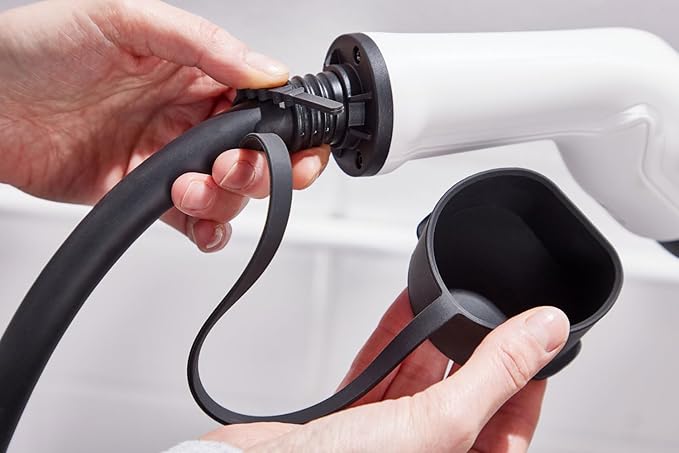 Person plugging Type 2 EV charging cable connector into home EV charger socket close-up view