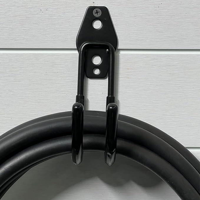 Black metal J-hook wall bracket holding coiled EV charging cable mounted on grey wall