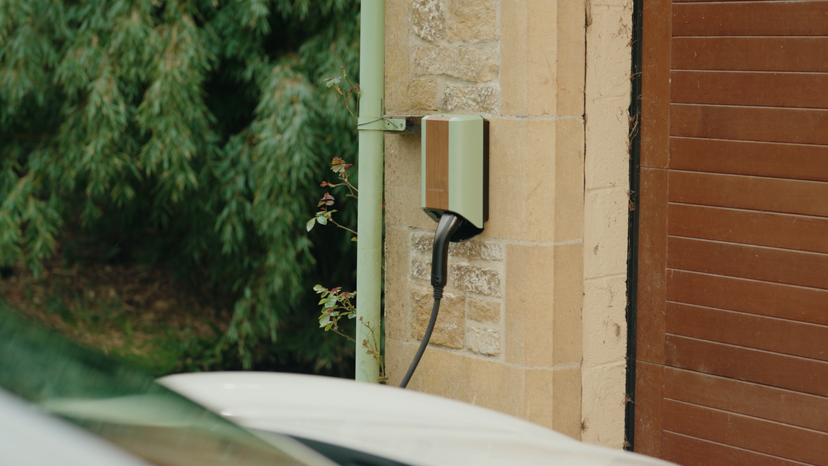 Andersen A3 EV charger in wood quartz finish installed on stone wall with car charging - buy premium home charging point