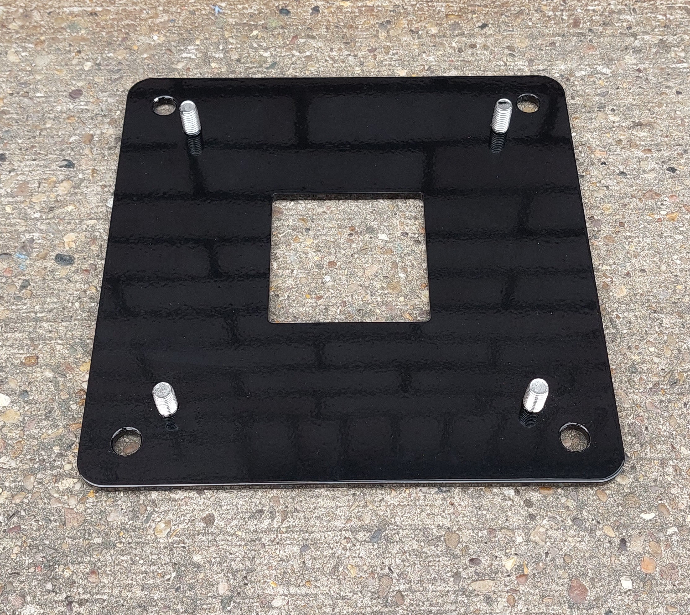 EV block mini pedestal black metal floor mounting base plate with bolt holes on concrete surface