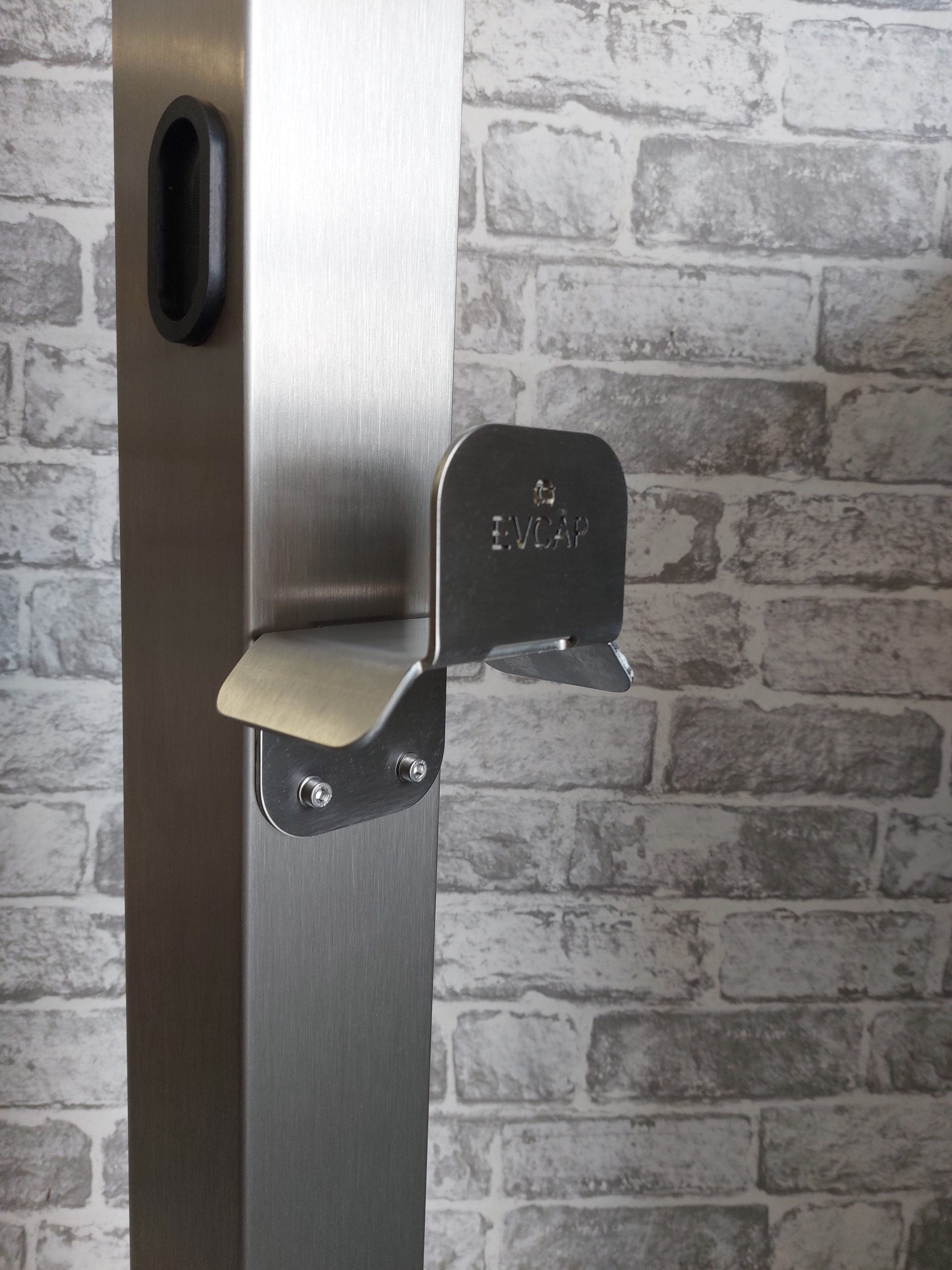 EV charger cable management bracket in stainless steel wall mounted close-up view against brick wall