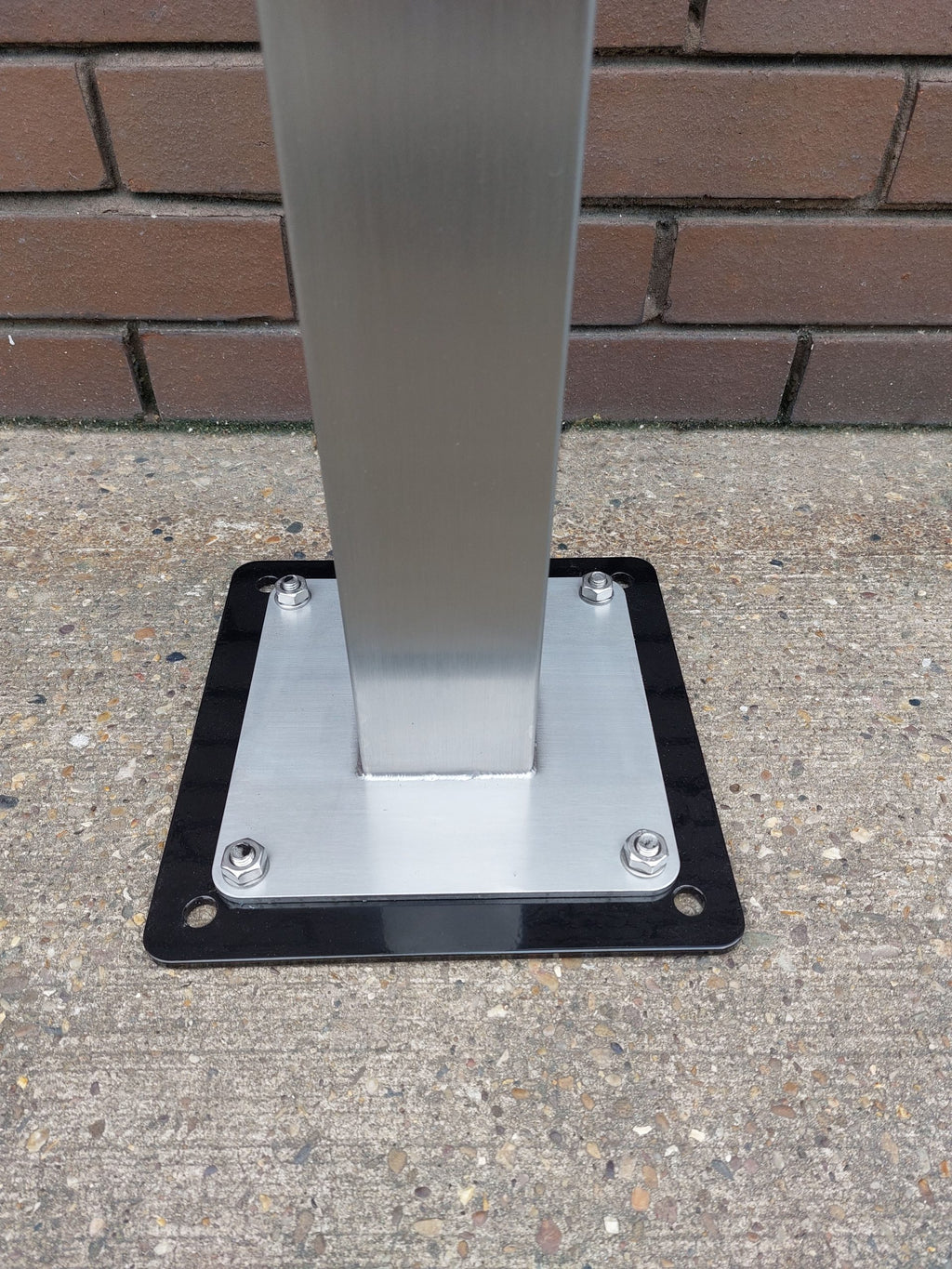 EV charger pedestal floor mounted base installation showing metal post and mounting plate on concrete