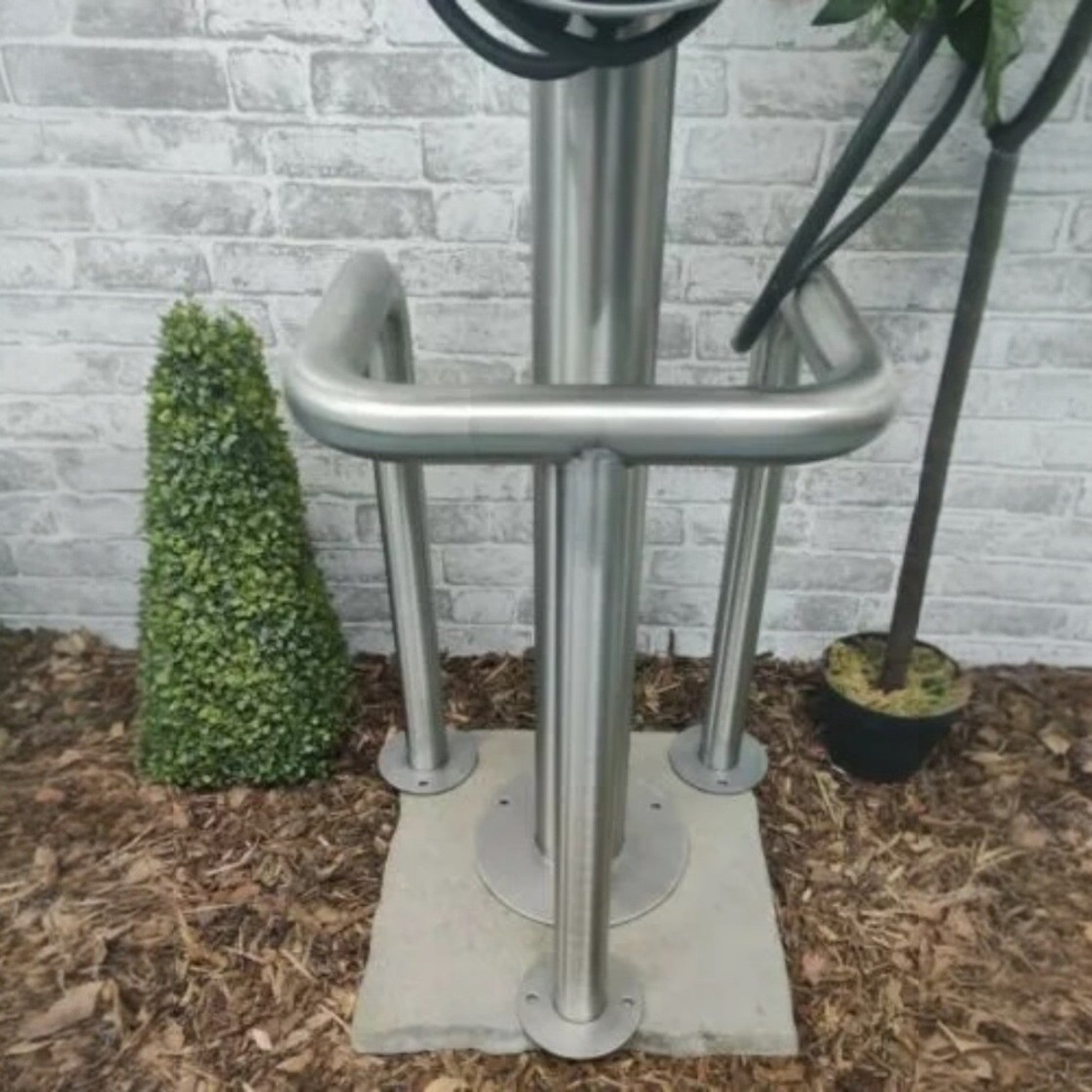 EVCAP Small Wrap EV charger stainless steel cable tidy post installed outdoors against brick wall with cable wrapped