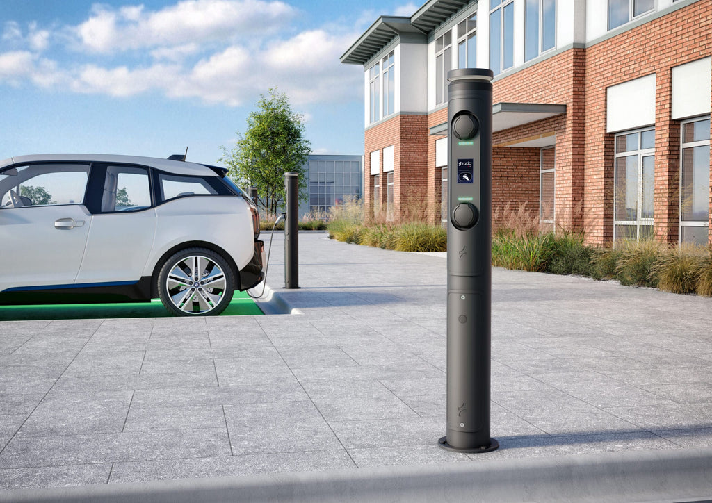 Ratio iO7 bollard EV chargers in daylight install at brick office building with BMW i3 plugged in to one of two iO7 posts on concrete tile paving