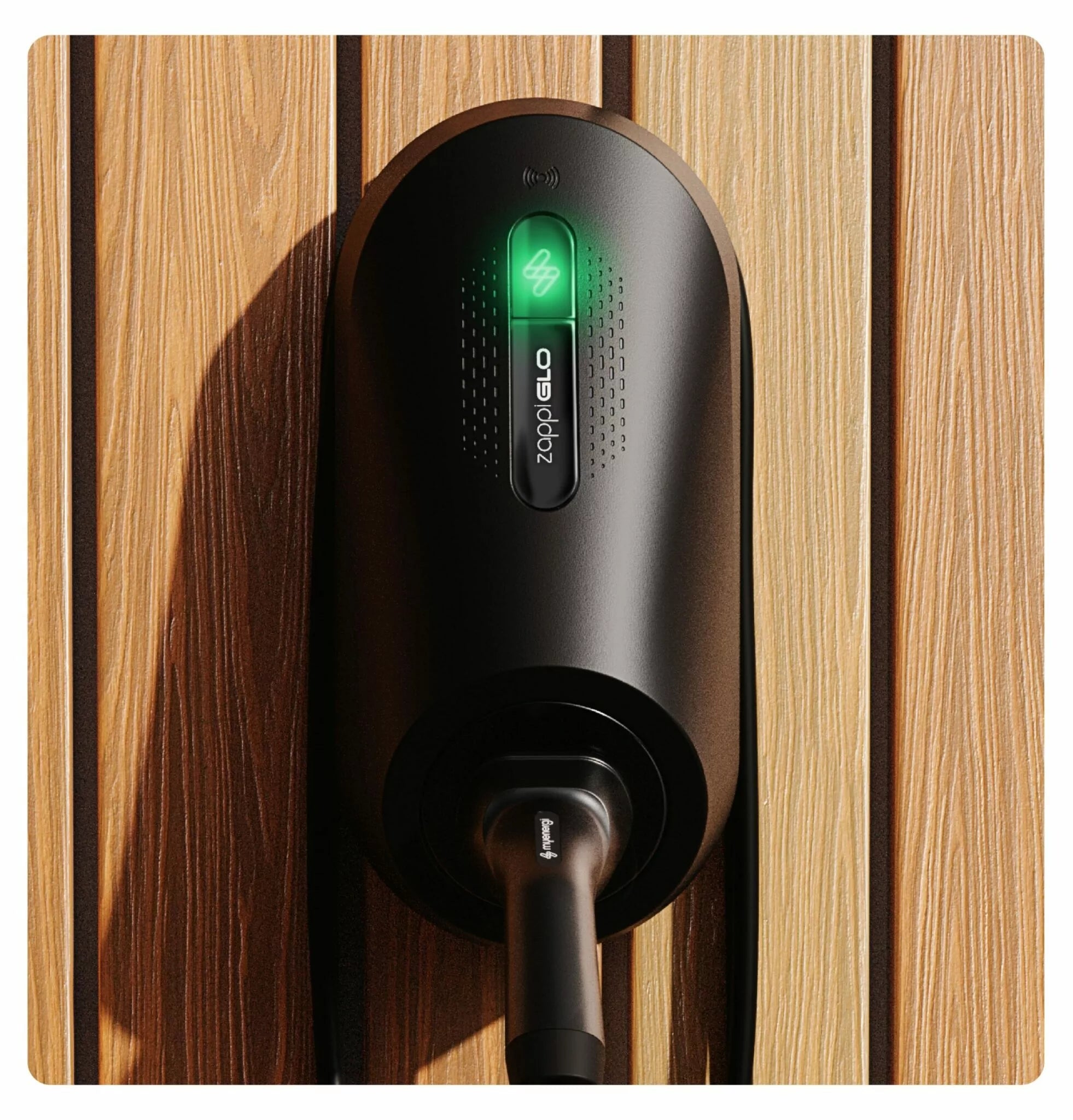 Myenergi Zappi GLO tethered home EV charger in black mounted on natural wood slat wall with illuminated green zappi logo and Type 2 cable connected at base