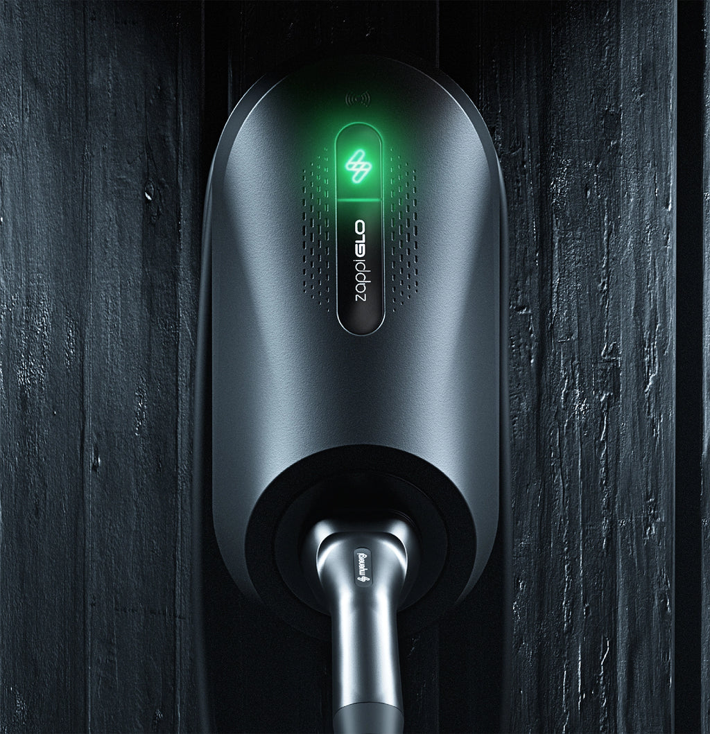 Myenergi Zappi GLO illuminated home EV charger in black mounted on dark wood slat wall with green zappiGLO logo glowing and Type 2 cable plugged in below